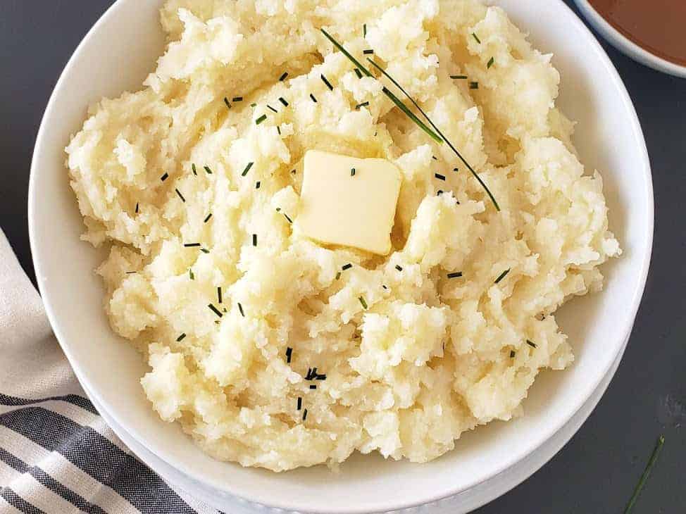 A close up image of bowl filled with mashed potatoes made from scratch at home using electric pressure cooker. 