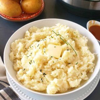 Creamy and fluffy Instant Pot mashed potatoes served with butter and chives.