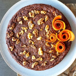 Date Sweetened no frosting carrot cake with walnuts served on the plate with carrot roses as garnishes.