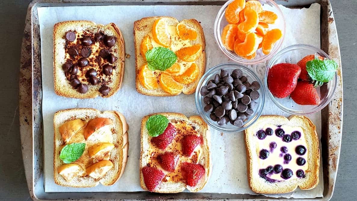 Horizontal image of various custard yogurt toasts made in the air fryer and topped with different fruits.
