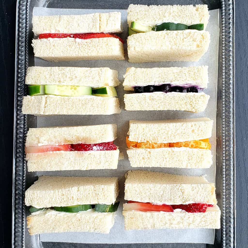 After tea sandwiches with sweet and savory flavors displayed on serving platter.
