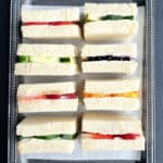 Afternoon tea sandwiches with sweet and savory flavors displayed on serving platter.