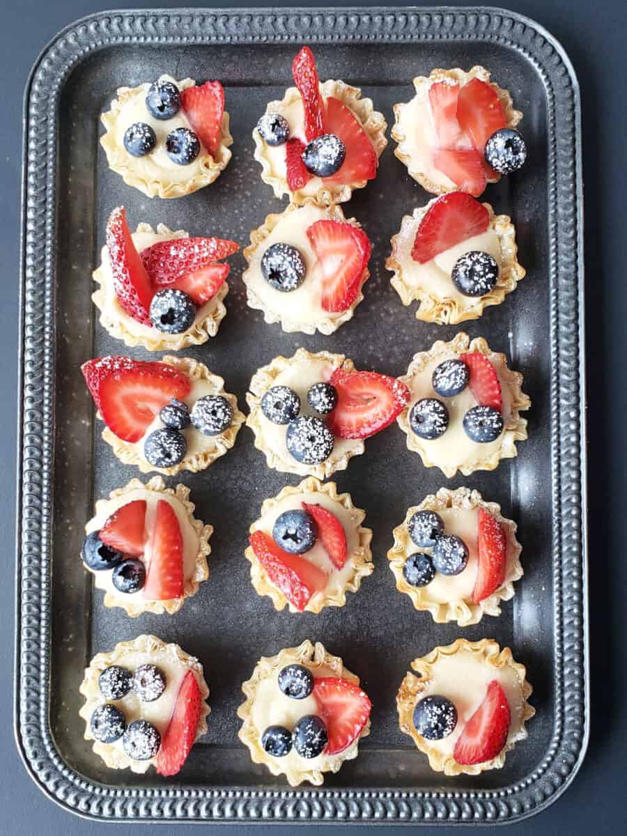 AN overhead image of a party tray full of red, white and blue themed cheesecake bites arranged in a rows. 