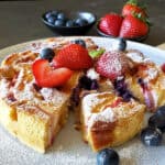 Cream cheese bread pudding which also tastes like cheesecake bread pudding sliced in pieces and decorated with fresh berries and powdered sugar.