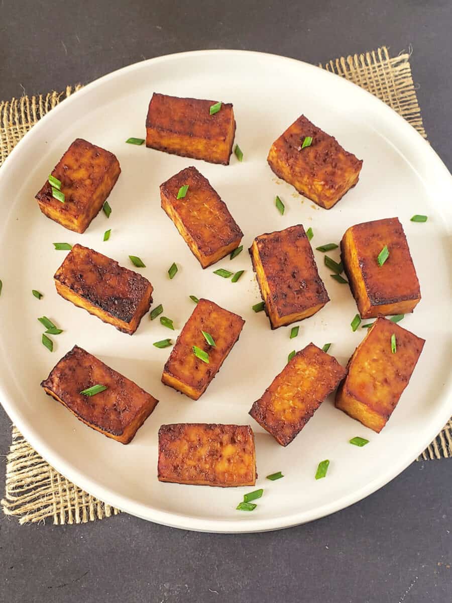 Pieces of smoked tofu served with garnishes.
