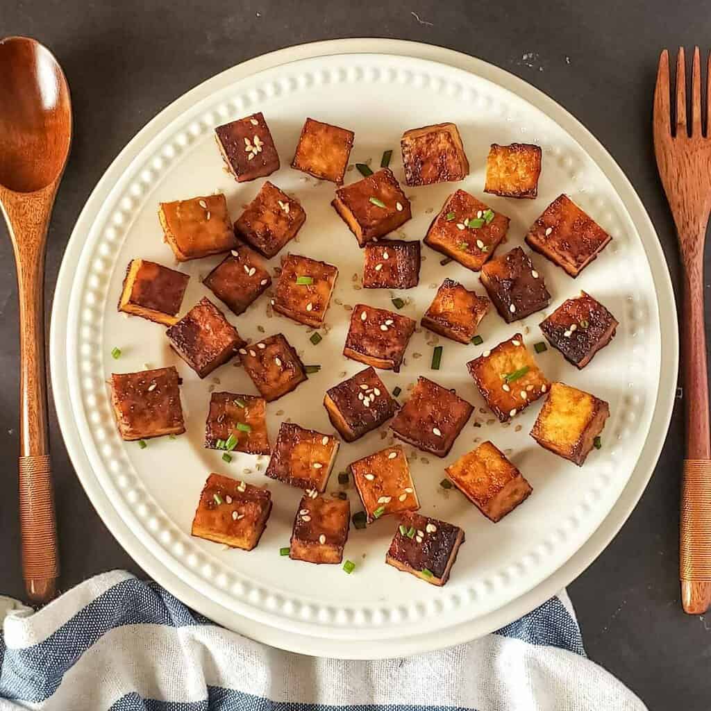 Air fryer tofu cubes served for dinner topped with garnishes.