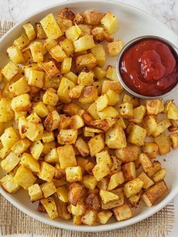 Crispy golden air fryer breakfast potatoes served with ketchup for hearty breakfast.