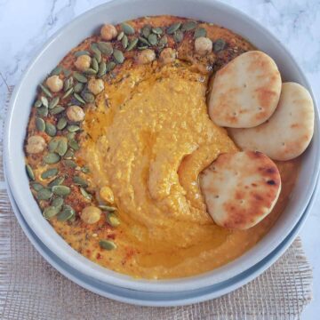 Creamy pumpkin hummus served with garnishes and dippers.