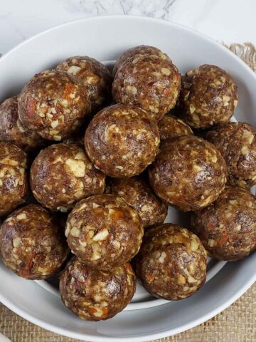 Naturally sweetened date balls with nuts stacked on the plate.