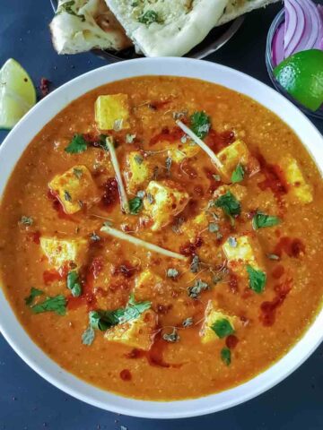 Achari paneer which is Indian dinner curry , made with soft cottage cheese cooked in pickle spice mix and onion tomato gravy, served for dinner.