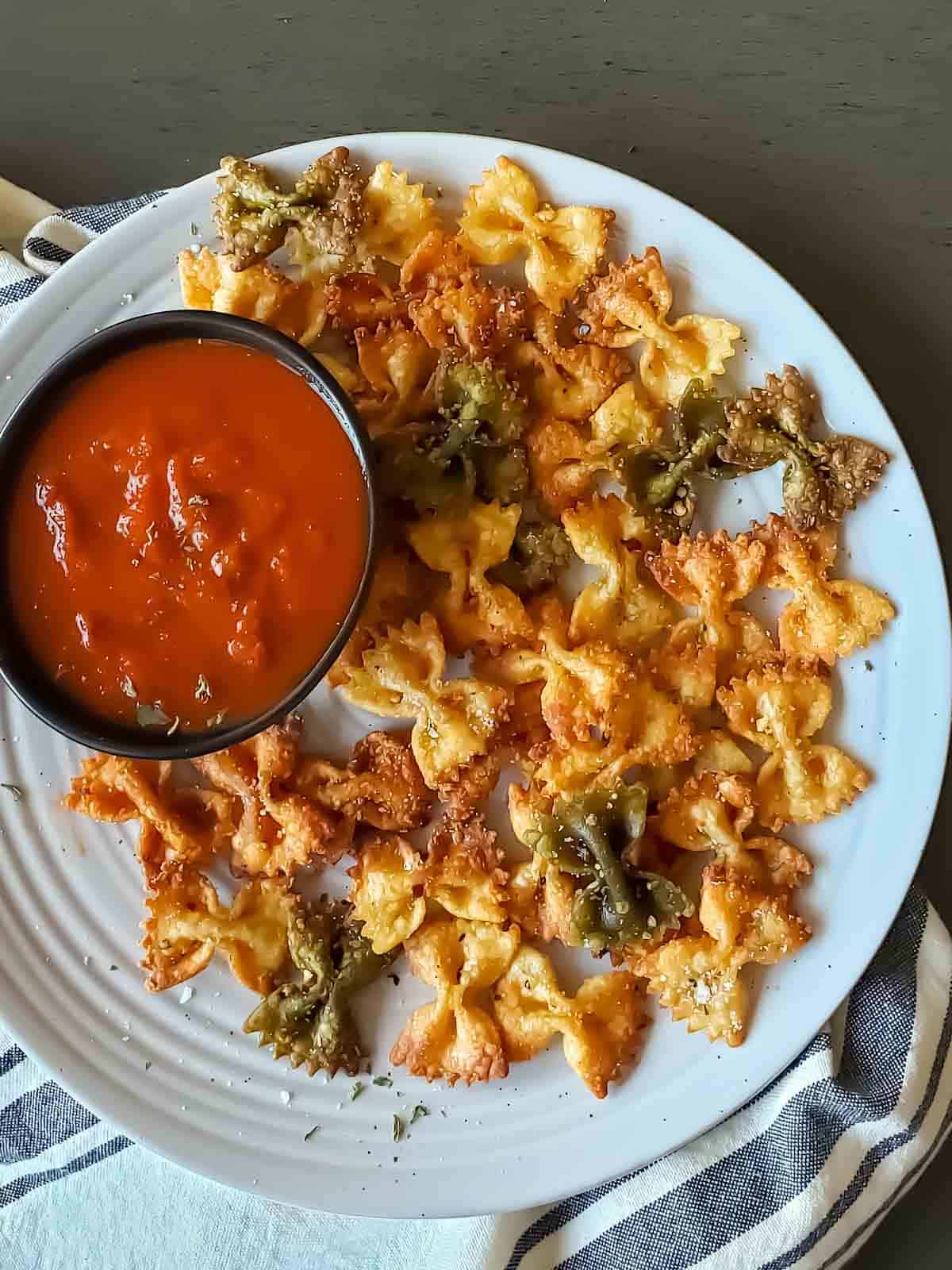 Crispy crunchy pasta chips with seasoning and dipping sauce served on a platter. 