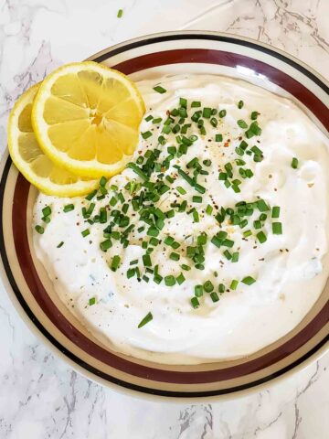 Creamy sour cream and chives dip with garnishes.