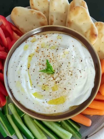 A bowl filled with whipped cottage cheese along with garnishes as a savory protein rich dip.