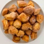 A plate full of crispy golden brown cinnamon sugar biscuit bites made in air fryer or oven.