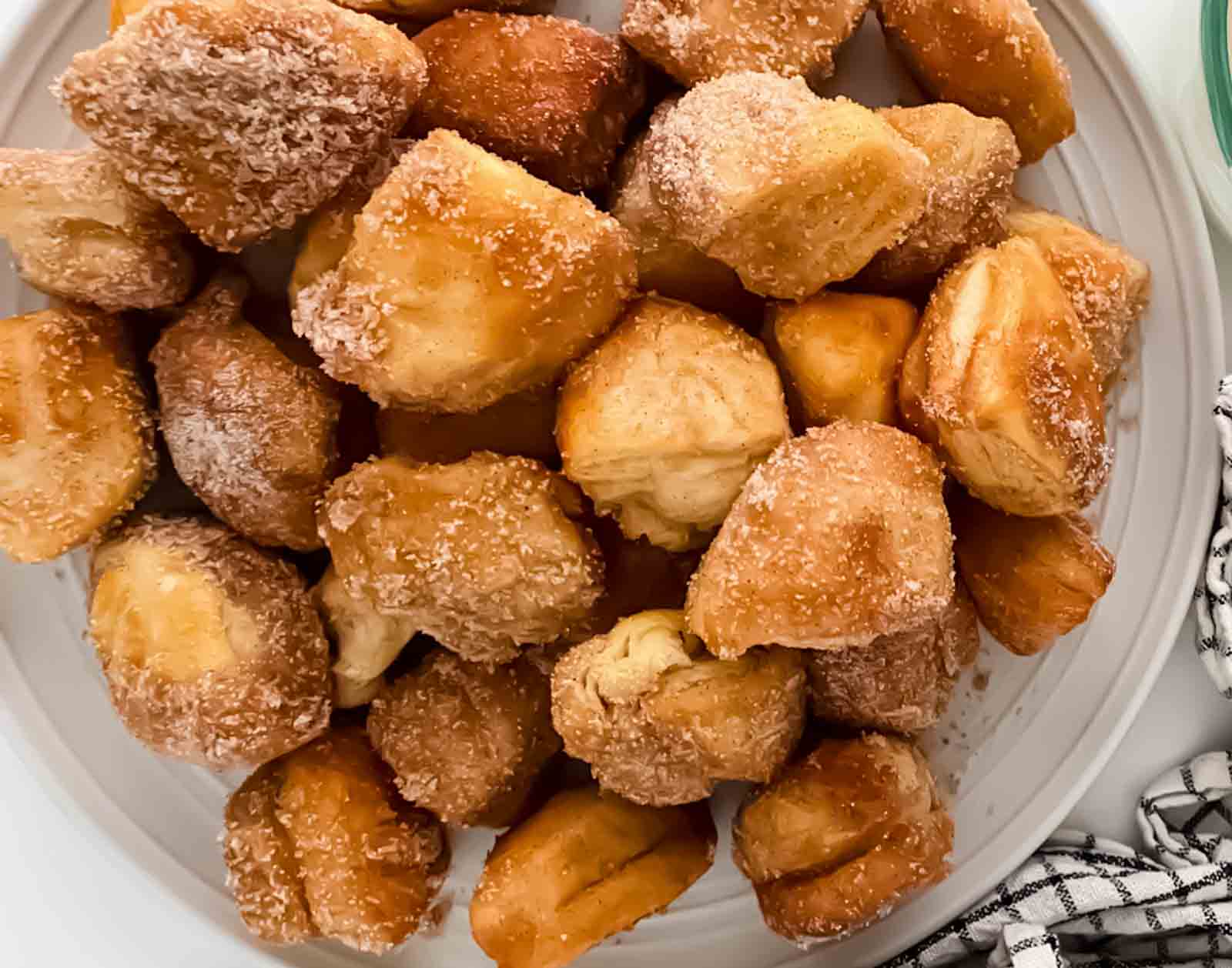 Close up of crispy air fryer cinnamon roll bites rolled in sugar and powder cinnamon for easy breakfast or snack.