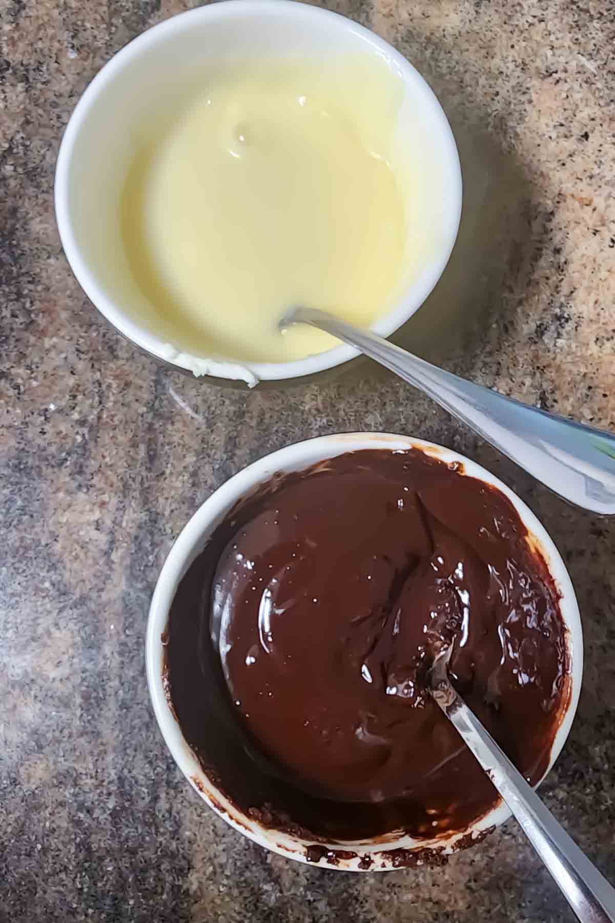 Two bowls of melted chocolate chips with spoons.