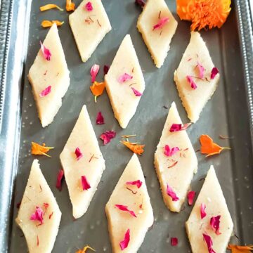 Badam burfi or almond katli made with almond flour served on tray with festive garnishes.