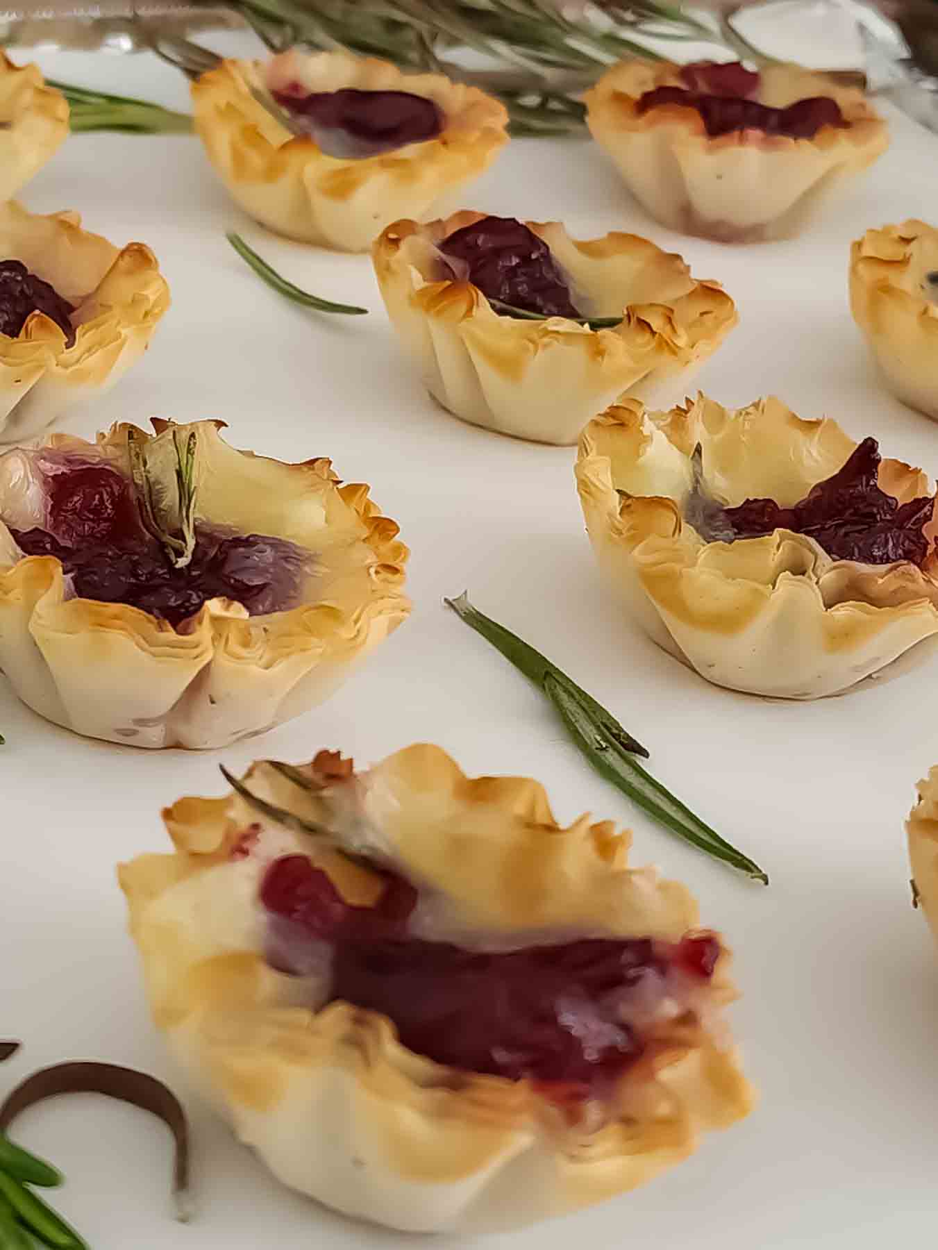 A close up of golden brown baked phyllo cup with cranberry and brie.