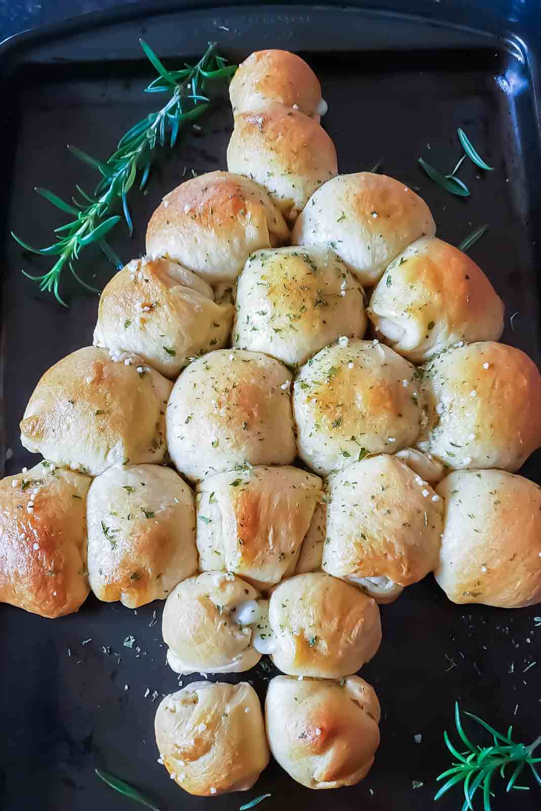 Christmas tree pull apart bread with butter and garlic garnish made with crescent rolls.