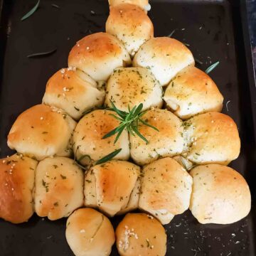 Christmas tree pull apart bread with crescent rolls and garlic butter herb seasoning served golden brown and garnished.