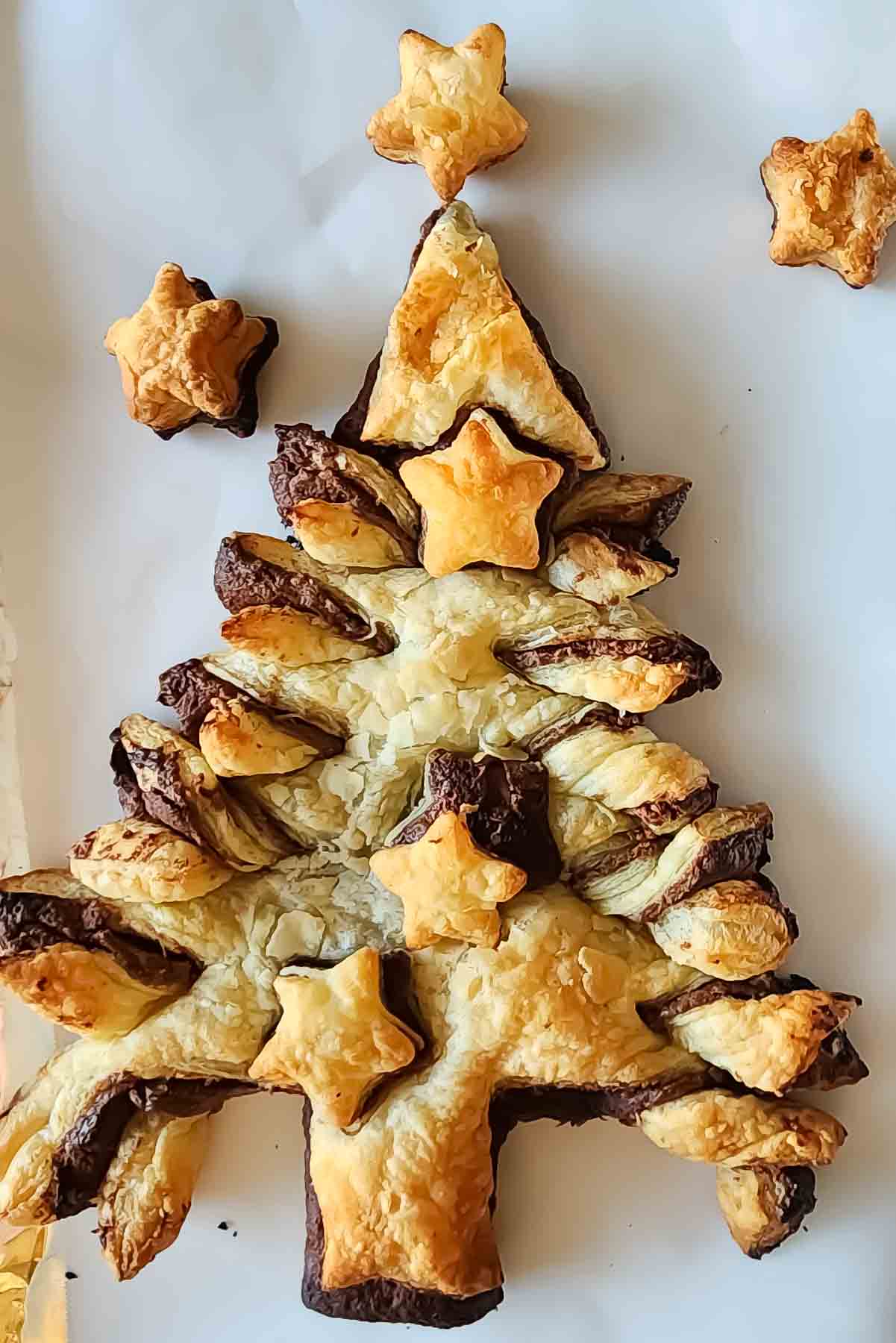 Golden brown puff pastry filled with chocolate hazelnut spread and shaped like Christmas tree , served as a holiday dessert.