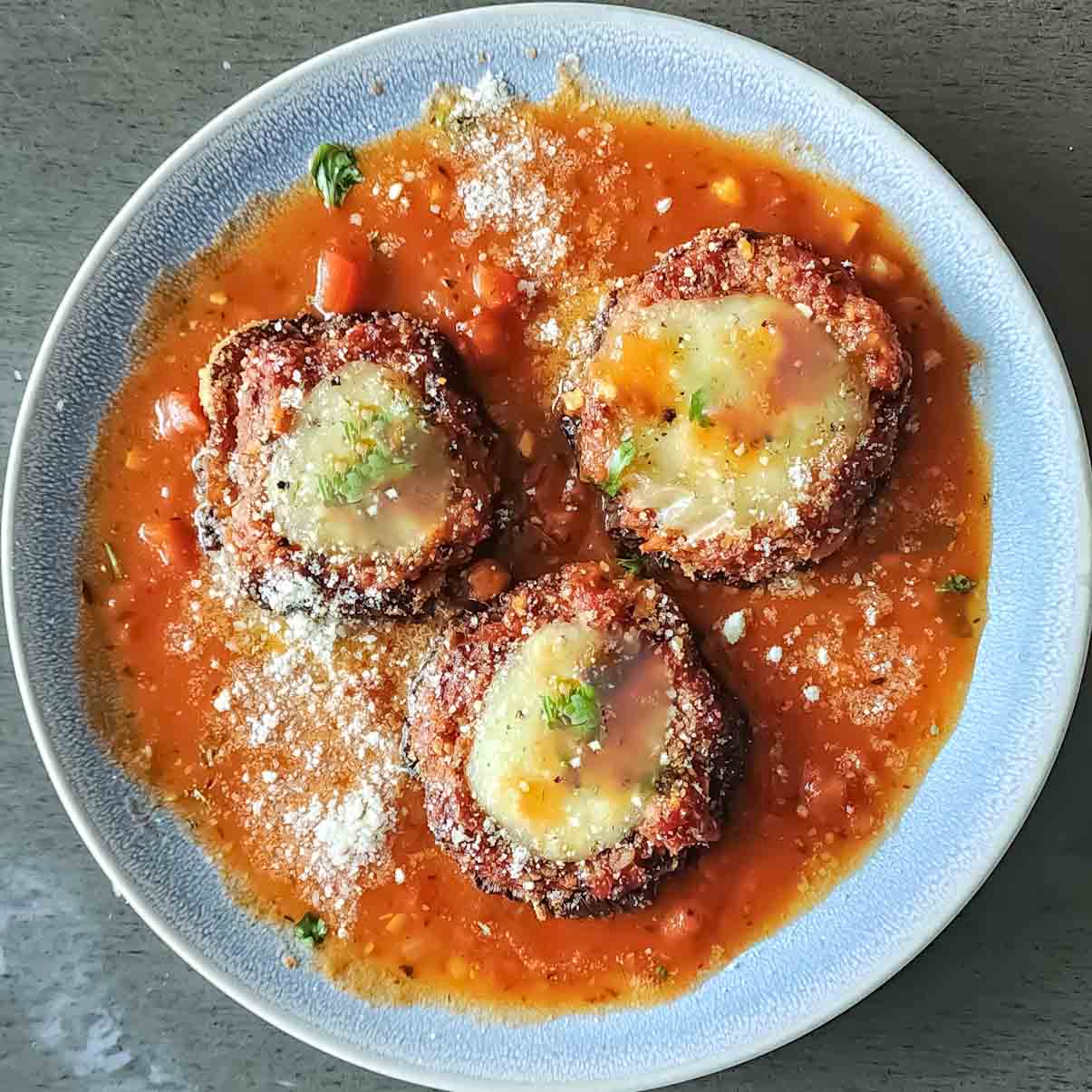 Air Fryer Eggplant Parmesan served with garnishes is a crispy, cheesy and healthier version of the classic Eggplant recipe. It is savory and comforting Italian food.