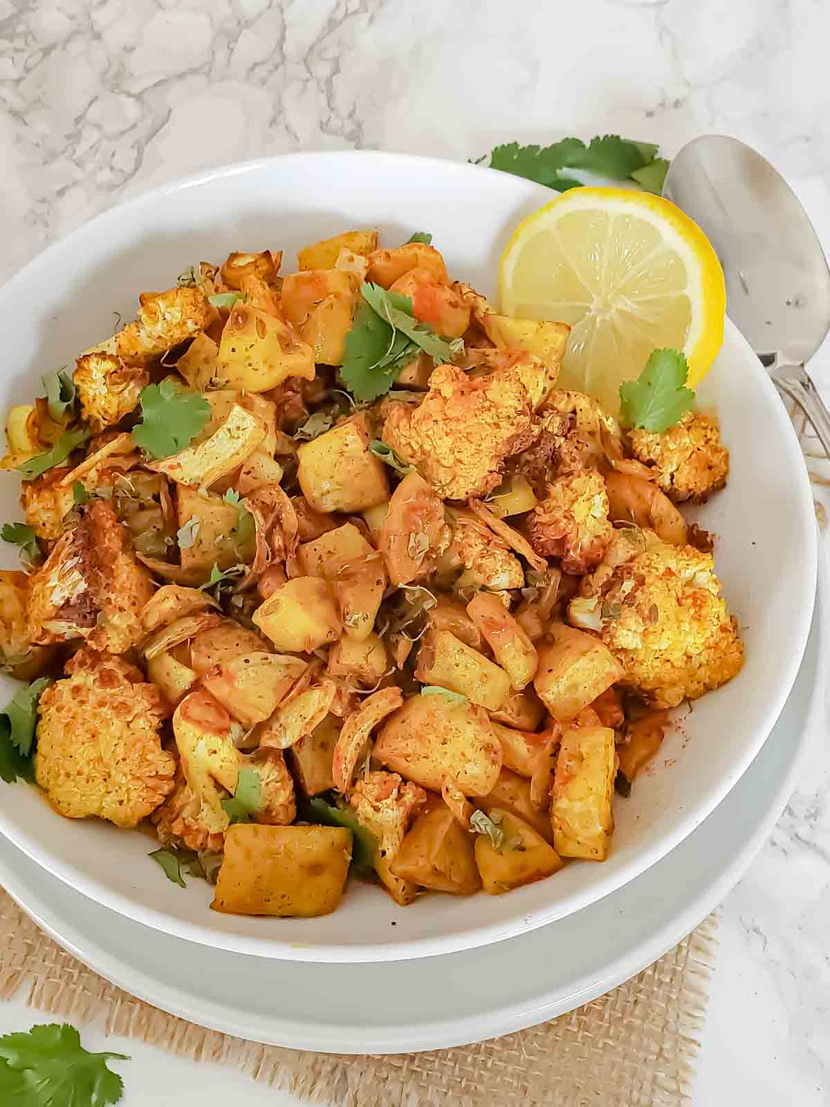 A bowl full of aloo gobi curry which is Indian cauliflower and potato dry sabji or stir fry with flavorful spices.