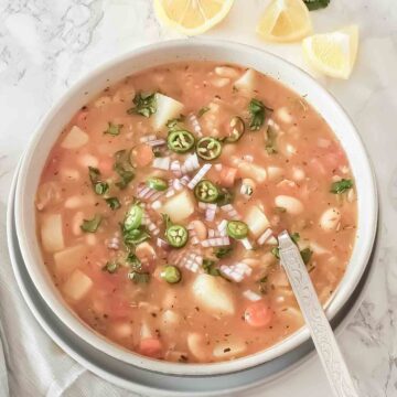 Thick, chunky and hearty Vegetable and beans green chile stew served in a bowl with garnishes for one pot cozy vegan dinner.