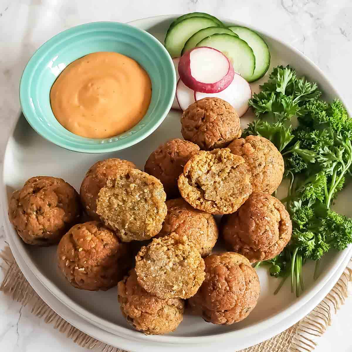 Baked falafel made with chickpeas and herb seasoning served as a middle Eastern Appetizer with dipping sauce.