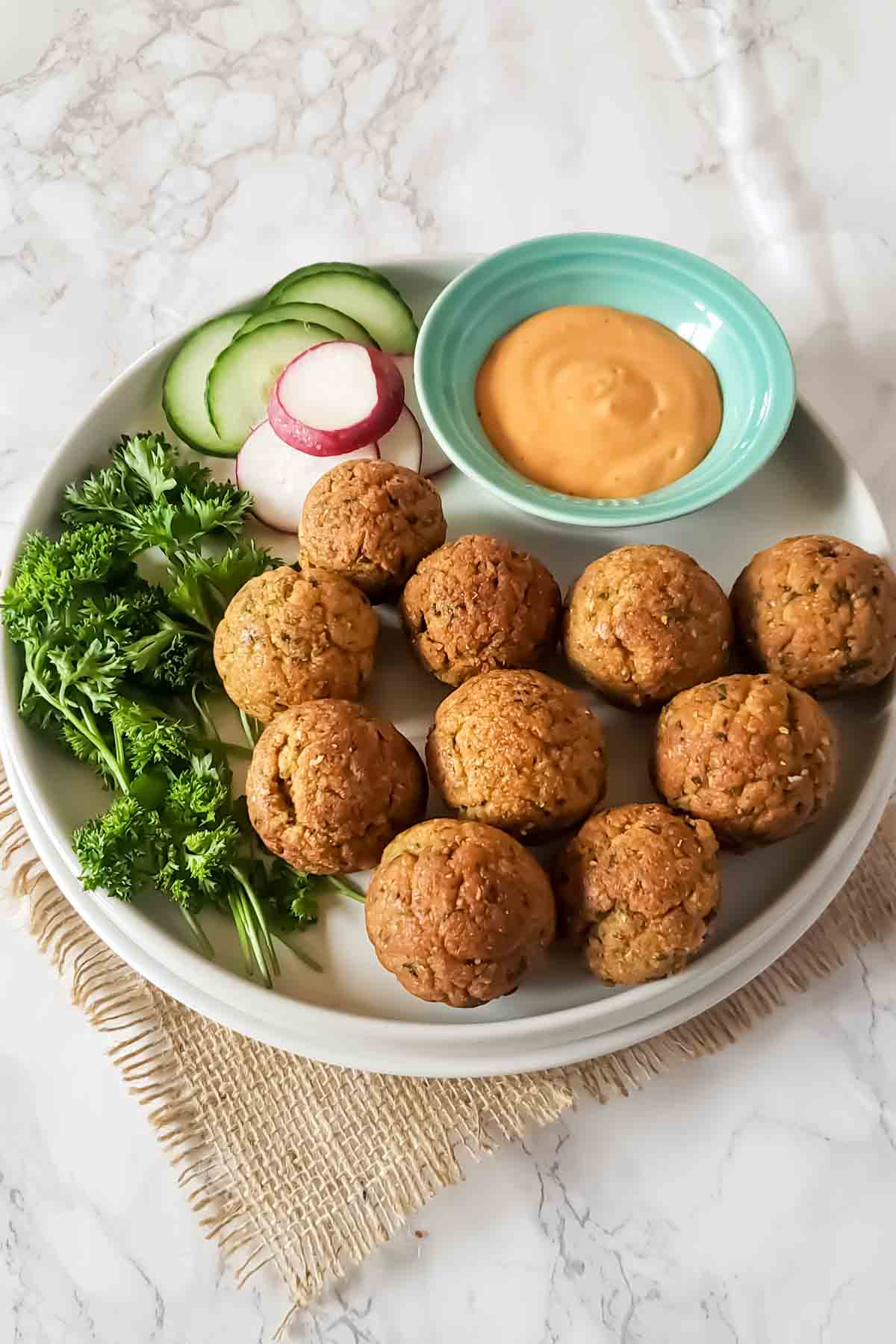 A plate full of homemade air fryer baked falafel served with dipping sauce. 