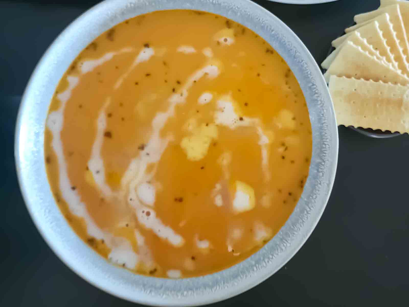 Creamy soup with roasted vegetables and coconut milk served in a bowl.