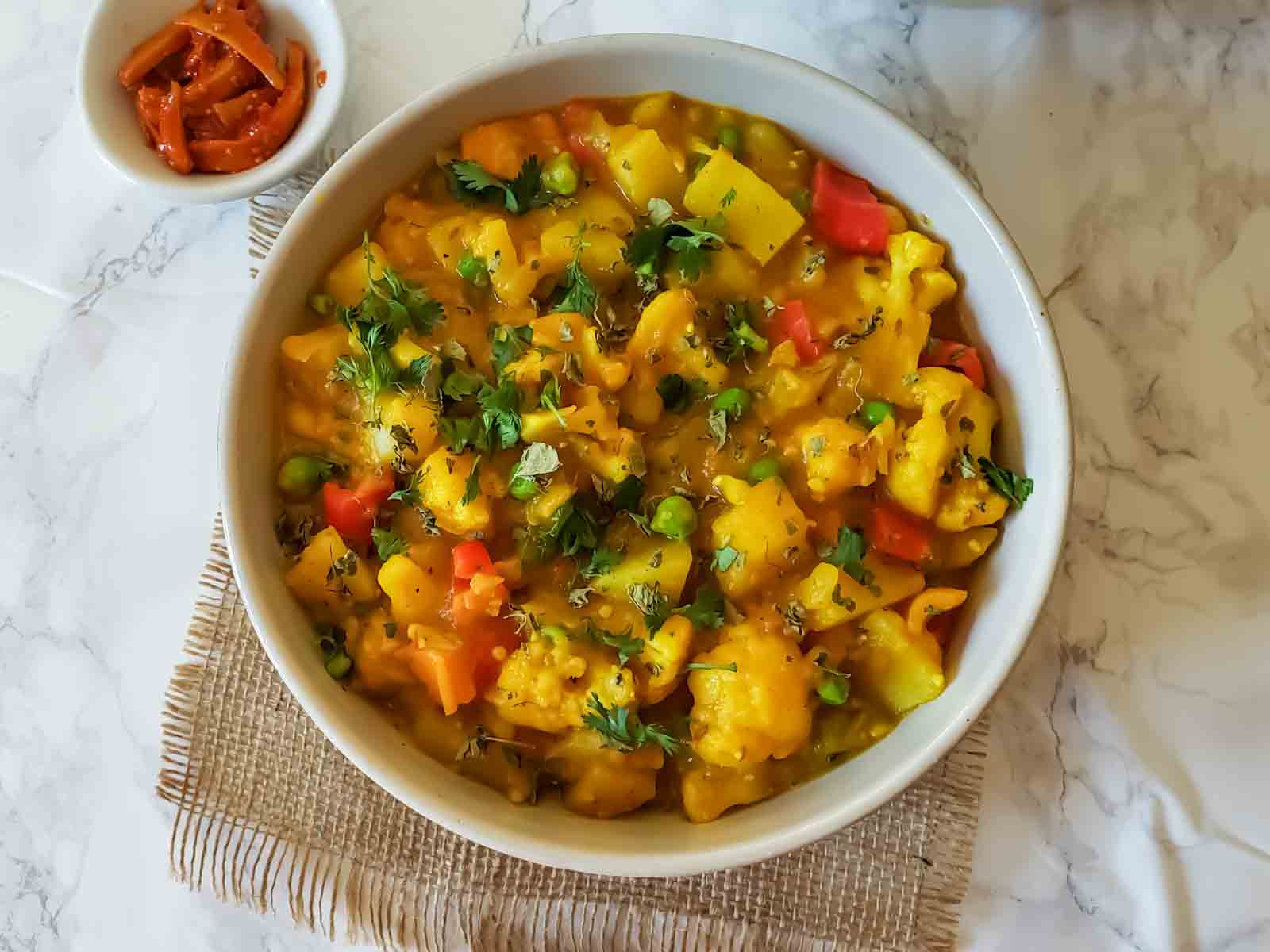 Golden indian vegetable curry recipe served with garnishes. 