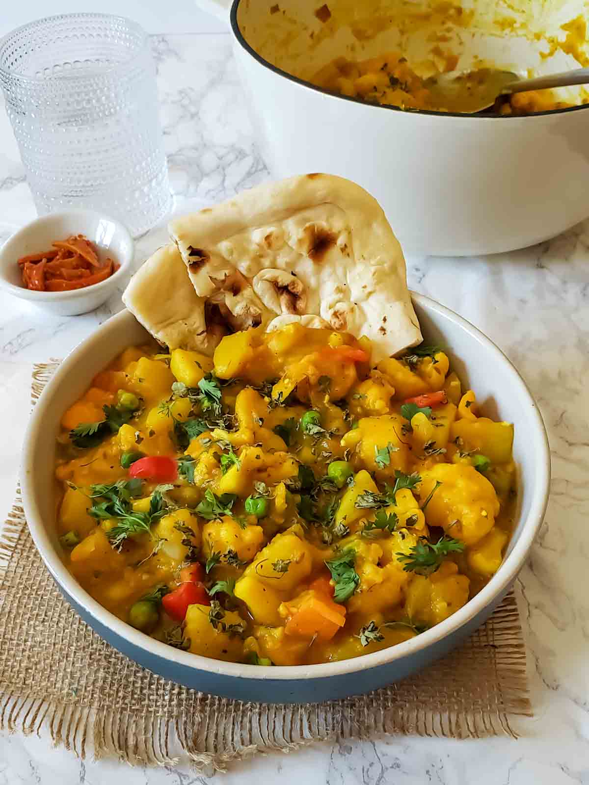 A dinner bowl full of vegetable curry recipe served with naan for a scrumptious vegan and gluten-free meal. 