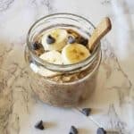 Almond butter overnight oats with almond milk served in a glass jar with wooden spoon for healthy and high protein vegan breakfast.