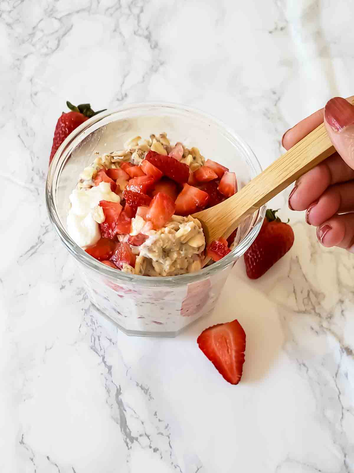A spoon full of creamy breakfast oats with strawberries and cream.