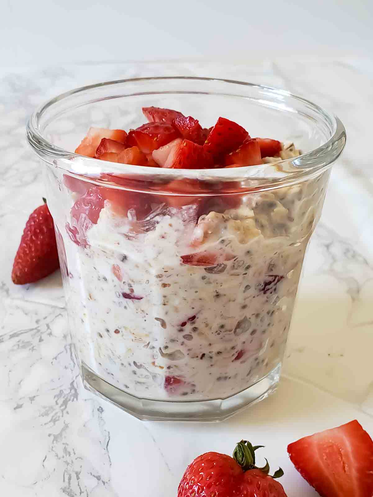 Overnight oats with strawberries and cream served in a glass jar.