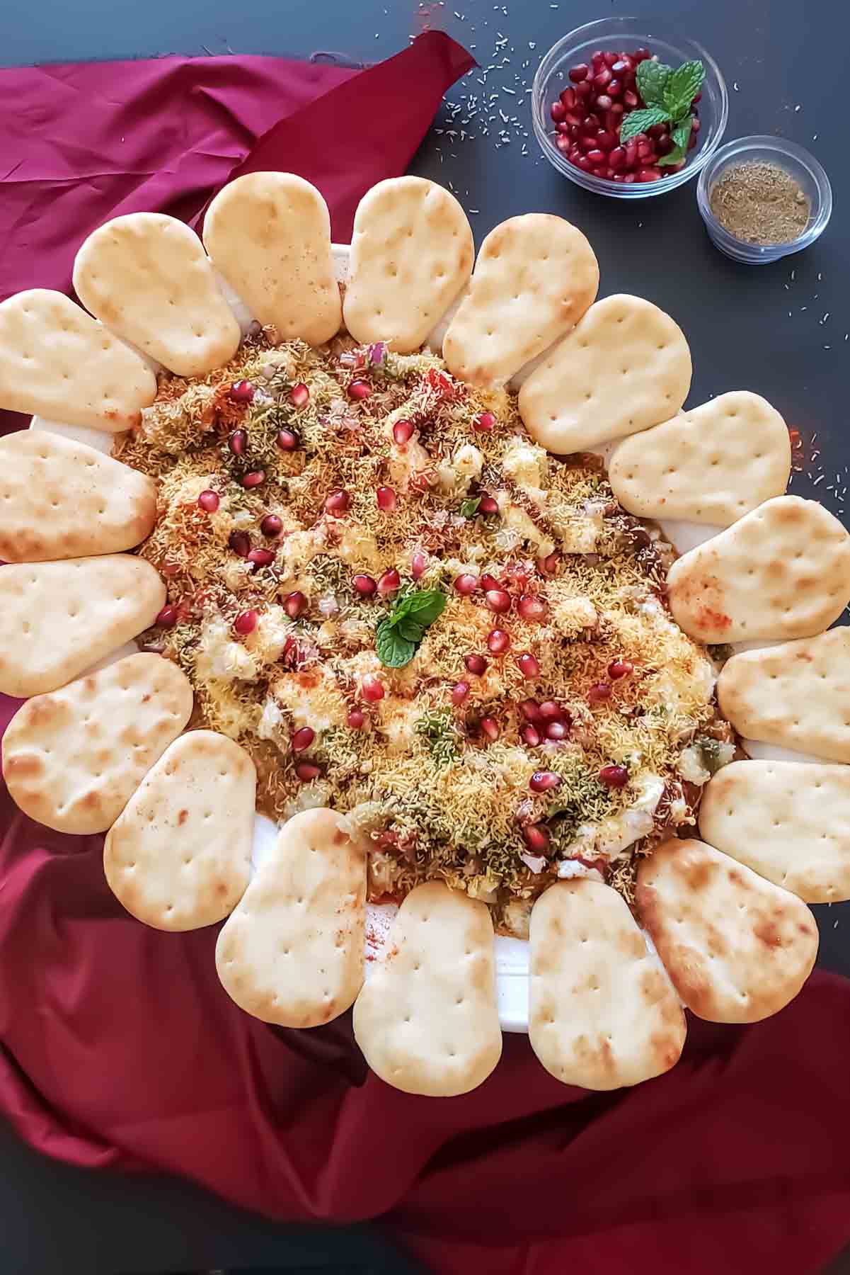 Indian 7-layer dip with chole, spiced potatoes and yogurt, chutneys and sev, served on a platter for delicious fusion party appetizer.