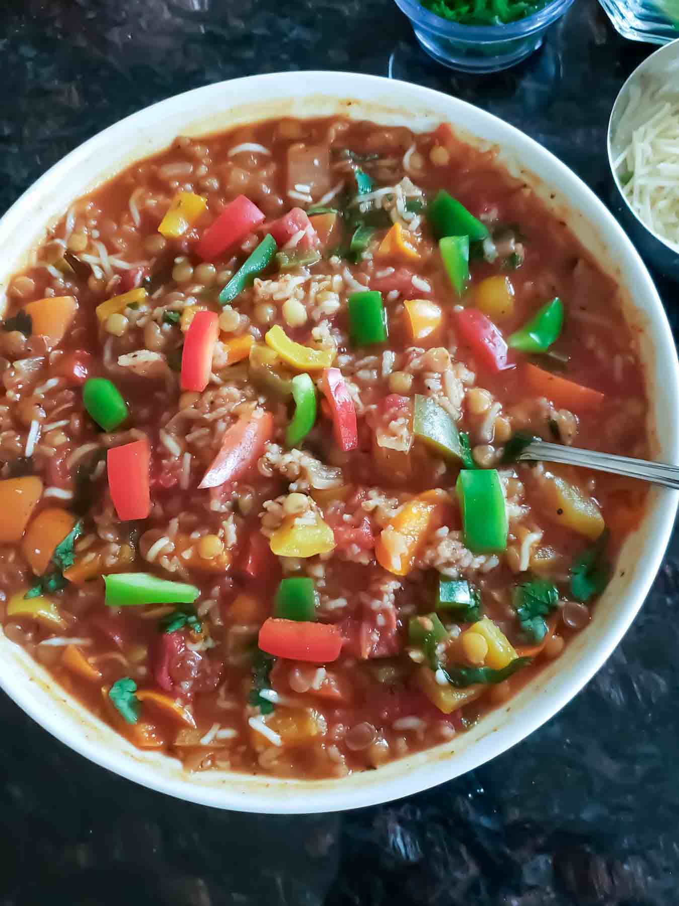 A close up showing cooked lentils, rice and bell peppers used in vegan stuffed pepper soup.