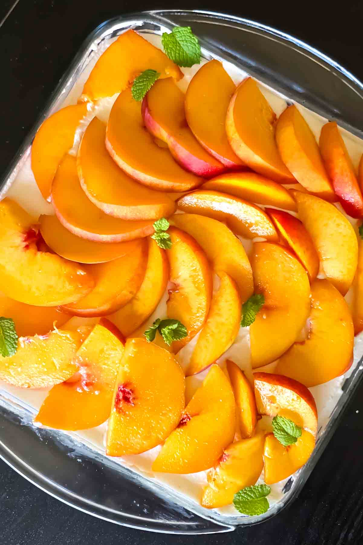 Peaches and cream cheesecake topped with fresh sliced peaches.