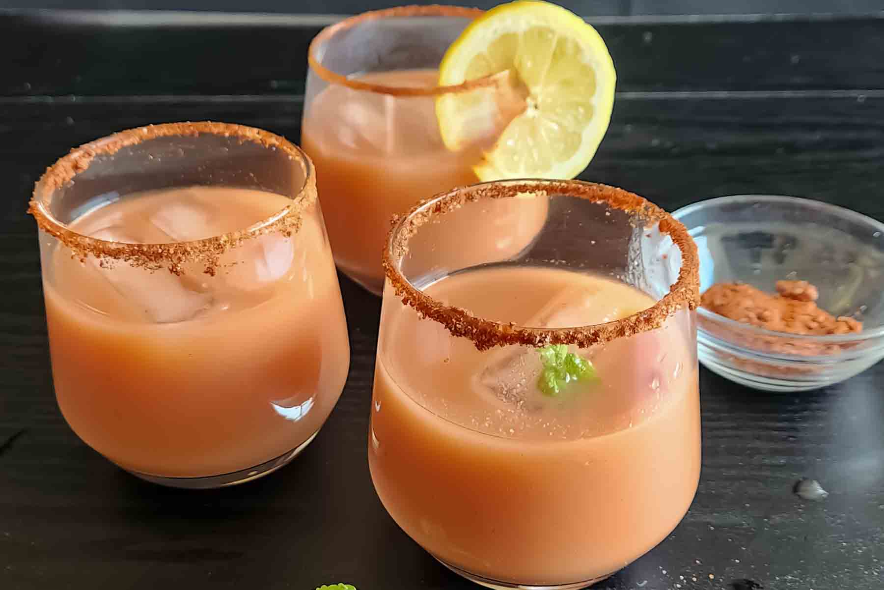Sparkling guava drink with lemon slices and fresh mint, served in glasses rimmed with chili lime seasoning.
