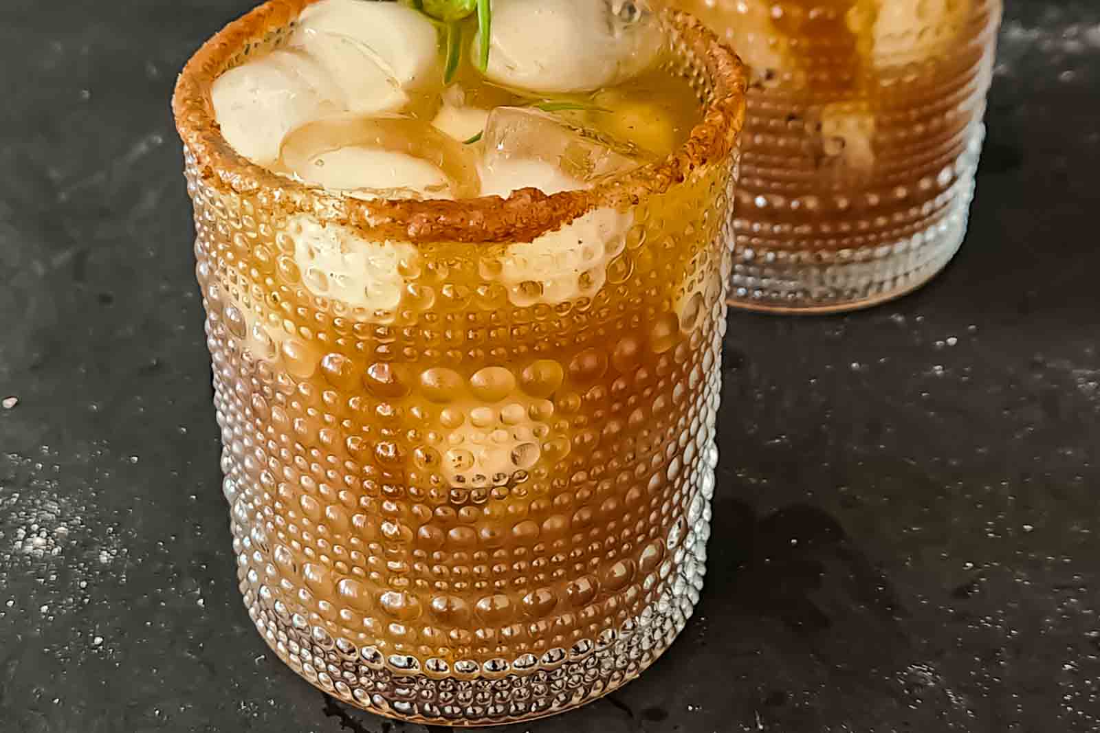 Tamarind mocktail with ginger ale and agave syrup served in a glass with a chamoy and chaat masala rim.