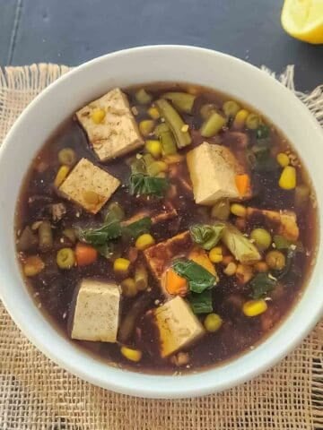 Tofu soup with frozen vegetables, miso, ginger and garlic in a bowl.